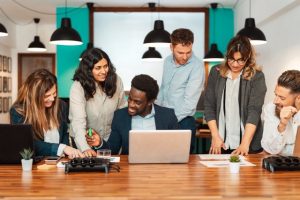 Colleagues gathered around a laptop in a bright, modern office
