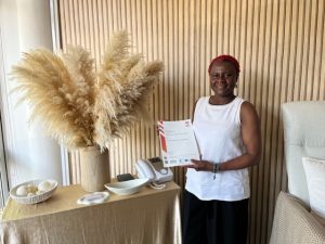 Woman holding up a training certificate in a spa treatment room